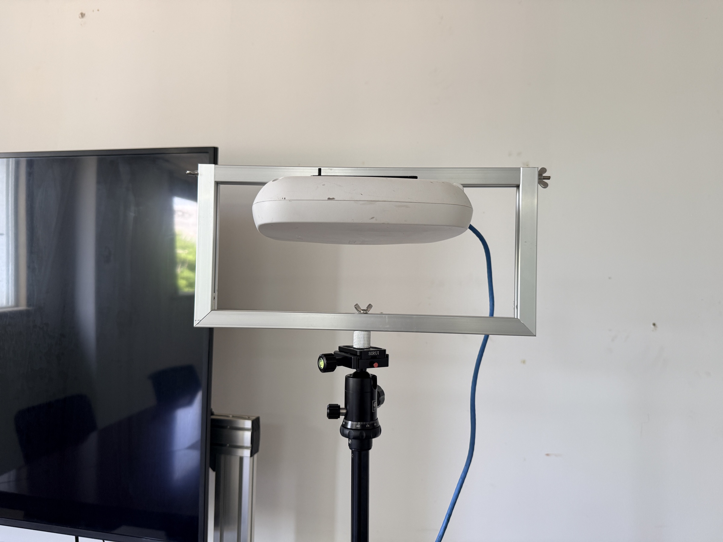 Close-up of an access point secured in an adjustable frame above a tripod head